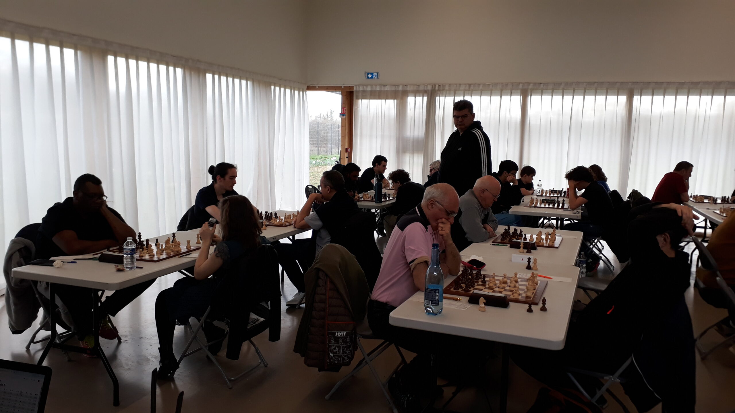 Joueurs d’échecs concentrés autour de plusieurs tables dans la salle des Mares Yvon à Saint‑Michel‑sur‑Orge.