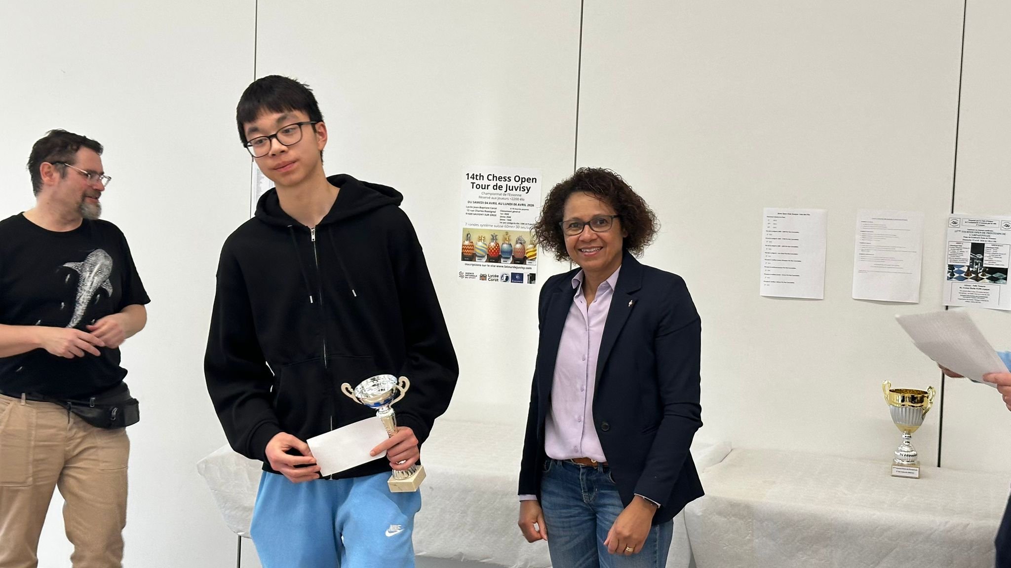 Jeune lauréat tenant une coupe lors de la remise des prix du tournoi d’échecs.