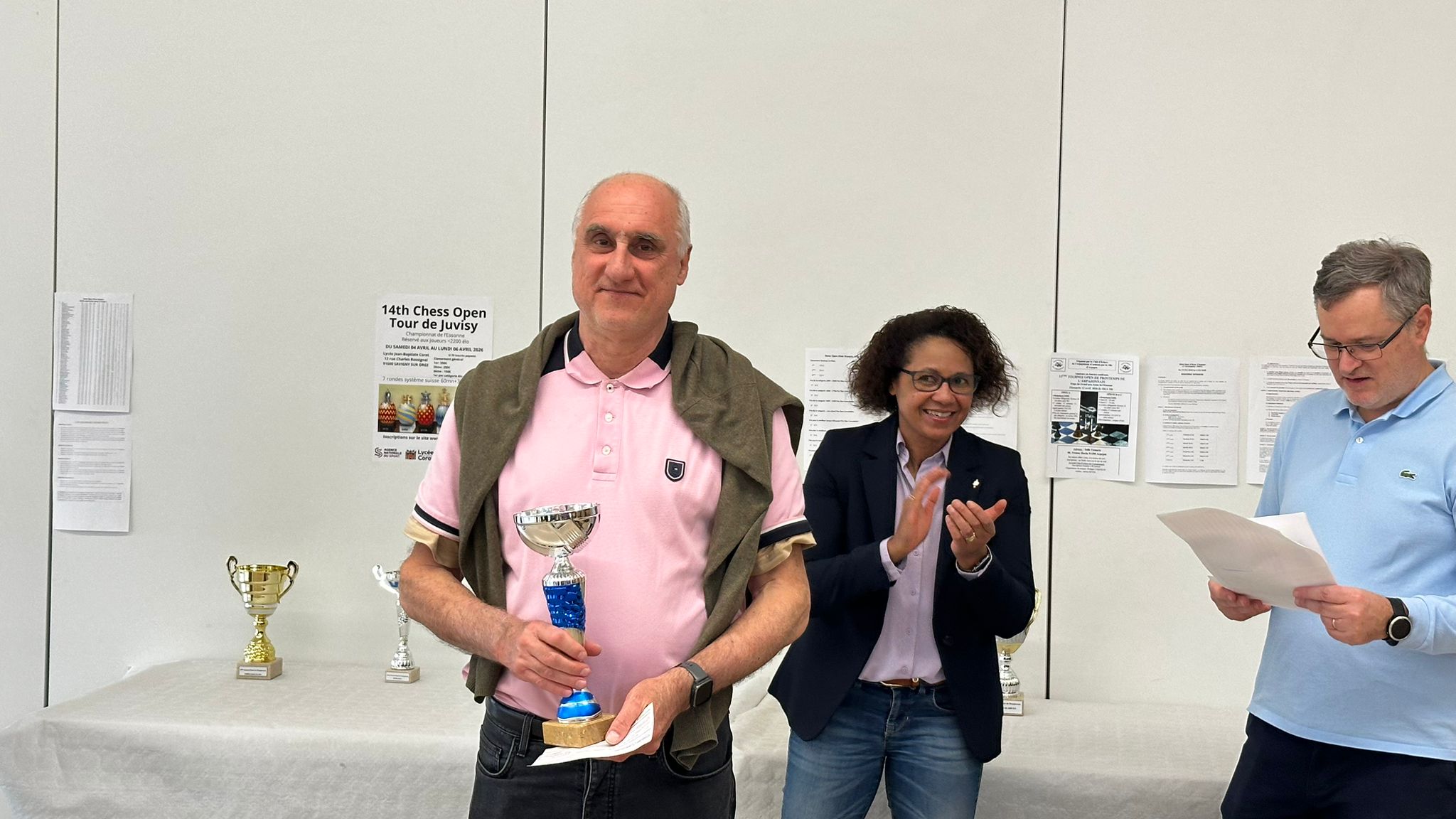 Lauréat tenant un trophée bleu pendant la remise des prix d’un open d’échecs.