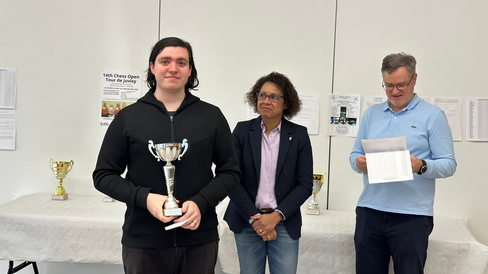 Lauréat tenant une coupe argentée pendant une cérémonie de remise des prix d’échecs.